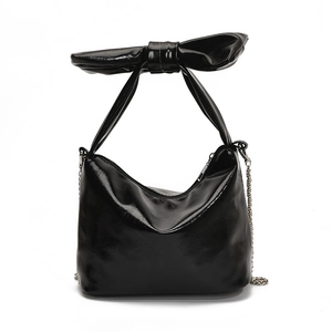 Glossy black patent leather tote bag with large decorative bow handle and silver chain