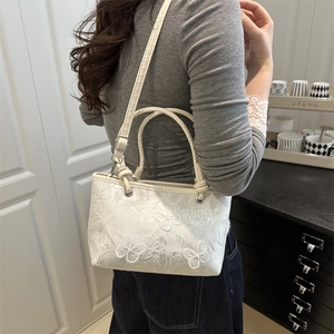 Sac cabas blanc en dentelle avec broderie papillon et bandoulière sur mannequin