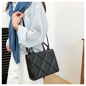 Detail of black large quilted tote bag showing rhombus stitching and shoulder strap