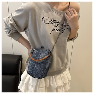 Polka dot denim mini crossbody bag with leather handle and metal chain shown on model