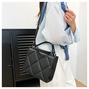 Detail of black quilted tote bag with gold hardware and adjustable shoulder strap
