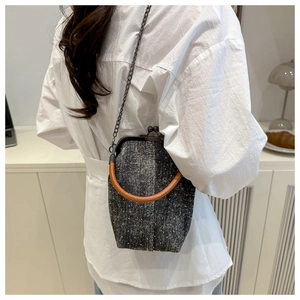 Detail of vintage gray tweed bag featuring brown leather handle and metal chain strap