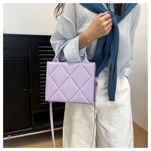 Detailed view of a lavender quilted tote bag with top handle and slender shoulder strap