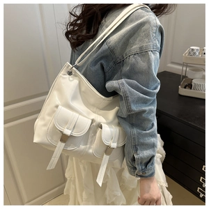 Close-up of a white patent leather tote bag with functional pockets and long straps