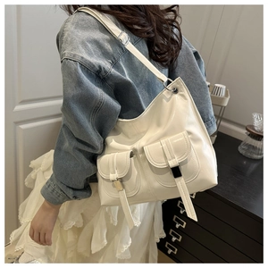 Side view of woman wearing a creamy white faux leather tote bag with double front pockets
