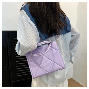 Detail of purple quilted tote bag with triangle stitching and round handles shown on a model