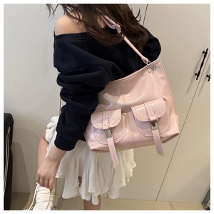 Detail of light pink patent leather tote bag featuring dual front pockets and silver buckles