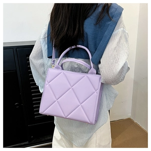Detail of light purple quilted tote bag with dual handles and adjustable shoulder strap