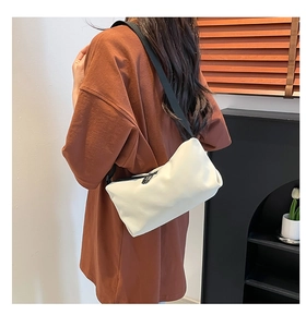 Rückansicht der beigefarbenen Crossbody-Tasche mit schwarzem Nylongurt am Modell