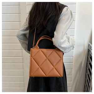 Rear view of a model wearing the caramel brown quilted tote bag with a fine shoulder strap