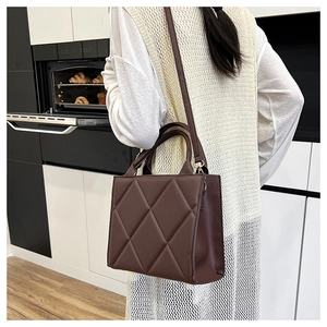 Close-up of dark brown quilted rhombic handbag featuring matte synthetic leather and top handle