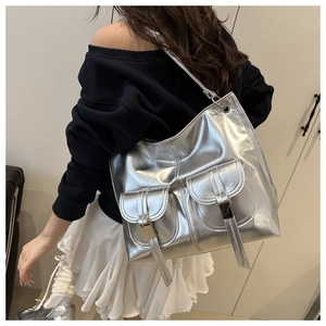 Close-up of metallic silver tote bag featuring dual front pockets and glossy hardware