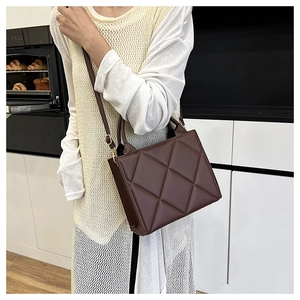 Detail of dark chocolate quilted tote bag with matte finish and gold-tone hardware
