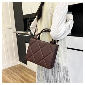 Detail view of coffee brown quilted tote bag with large diamond stitching and leather strap