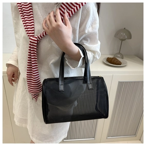 Détail du sac cabas en maille noire montrant la texture ajourée et les anses en cuir