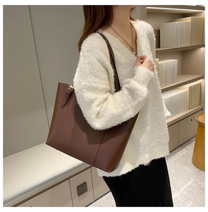 Detail of a brown leather tote bag with metal buckle and soft matte texture finish