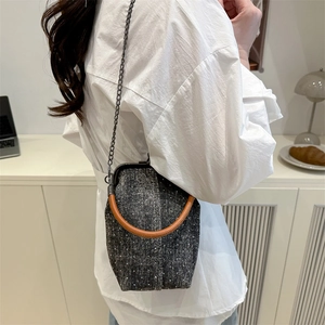 Retro grey tweed frame handbag with white dots and round top handle on a female model