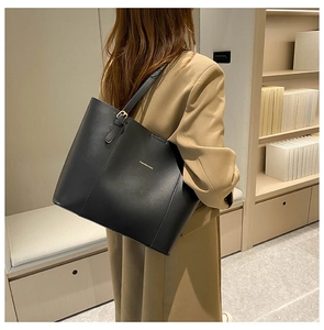 Fashionable black leather tote bag with gold lettering styled with a beige suit
