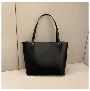 Close-up of black faux leather tote bag with gold logo and metallic strap buckles