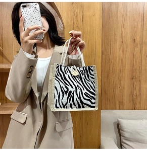 Detail of zebra pattern canvas tote bag with woven trim and decorative wooden button