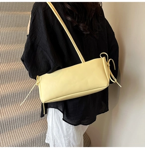 Detail shot of the side bow tie design and leather strap on this soft yellow underarm bag