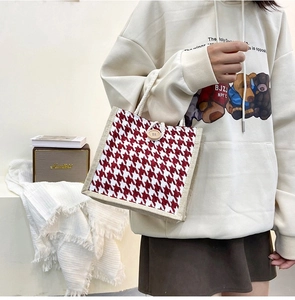 Detail of red houndstooth tote bag featuring wooden button closure and cotton rope handles