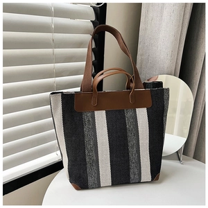 Dettaglio borsa tote vintage in tela a righe verticali con manici e dettagli in pelle marrone