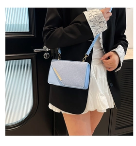 Modèle portant un sac bandoulière bleu clair avec texture tissée et métal doré