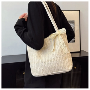 Detail of a woven straw tote bag with lace bow and cotton rope handle on shoulder