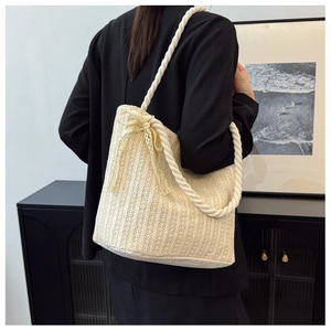 Detailed texture of woven straw tote bag featuring decorative lace bow and white cotton handles