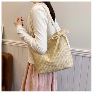 Detailed close-up of straw tote bag with white lace bow and cotton rope shoulder straps