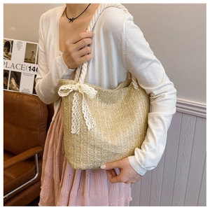 Detail of woven straw tote bag featuring delicate white lace bow and sturdy hemp rope handles
