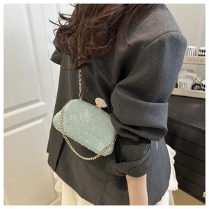 Detail of mint green textured evening bag with diamond clasp and gold chain strap