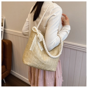 Close-up of woven straw bag with white lace bow detail and soft rope shoulder handle