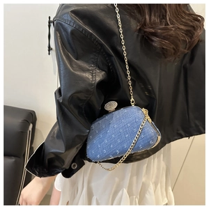 Detail of a blue denim polka dot bag with a pearl clasp and gold chain strap