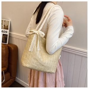 Detail of hand-woven straw tote with thick white rope handles and elegant lace bow