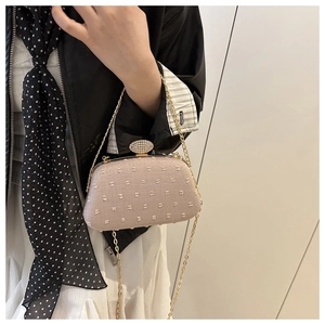 Detail of elegant beige evening clutch bag with gold chain and rhinestone clasp buckle