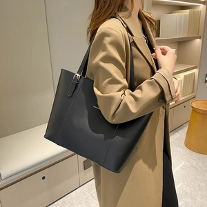 Minimalist black leather tote bag with large capacity shown on model in a cozy setting
