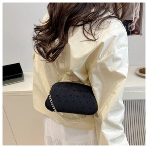 Detail der eleganten schwarzen Clutch mit Diamantverschluss und goldener Kette am Model