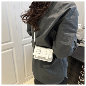 Detail of white mini square bag with double buckles and slim leather strap