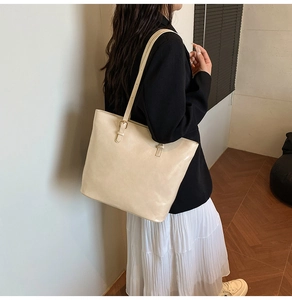 Detail of a cream beige leather tote bag with elegant gold metal adjustment buckles