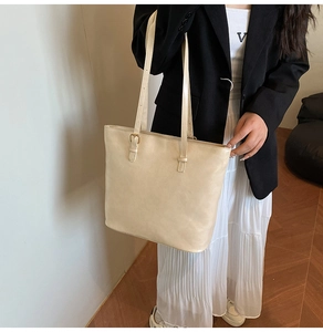 Detail of cream white tote bag with adjustable golden buckle and matte leather texture