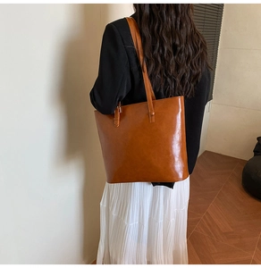 Detail of glossy brown faux leather tote with oil-wax texture and double shoulder straps