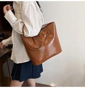 Detail shot of a large brown vintage tote bag showing its glossy finish and long strap