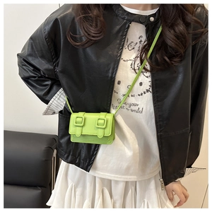 Detail of neon green mini crossbody bag featuring dual buckle closure on model