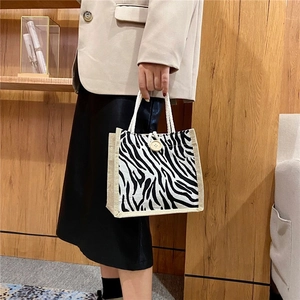 Fashionable zebra print tote bag with jute trim and wooden button on a female model