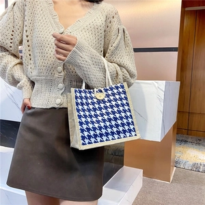 Blue and white houndstooth canvas tote bag with a wooden button and woven handles