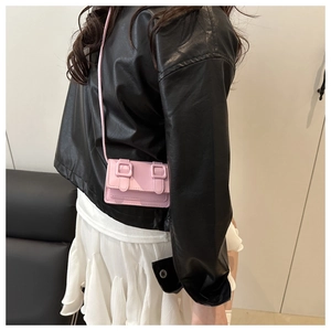 Close-up of a mini pink PU leather crossbody bag worn with a white pleated skirt