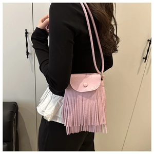 Detail of pink tassel crossbody bag with textured leather and fringe accents on model