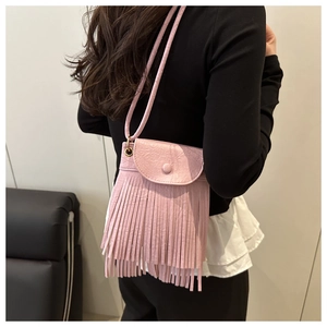 Detail shot of the pink faux leather crossbody bag with long fringe and flap button closure